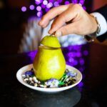 a person cutting a pear on a plate"